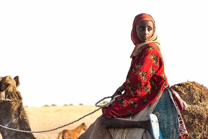 Nomad girl on a camel at a well