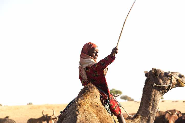 Nomad girl on a camel at a well