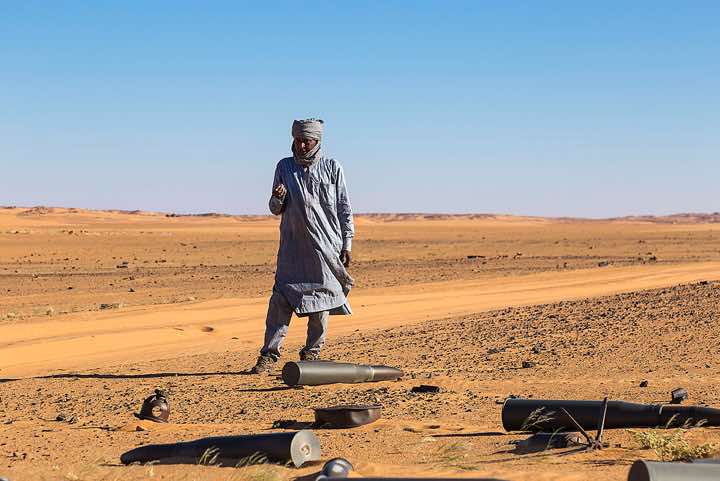 Driver Ibrahim exploring ammunition remnants in the desert sand