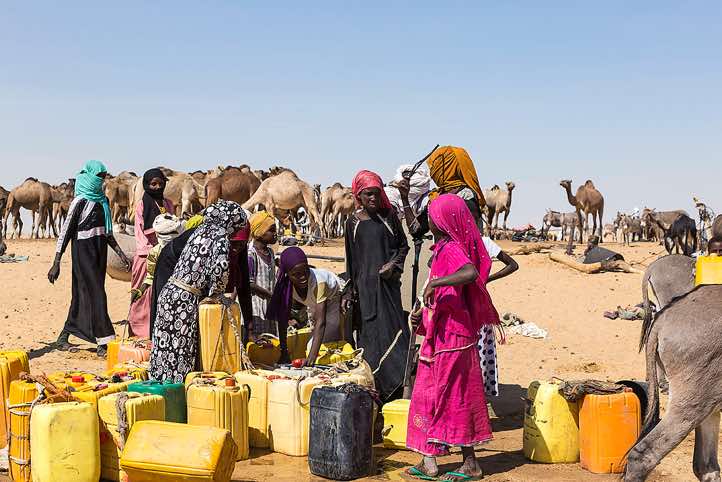At a well nomads water their herds and fill up their water canisters. The robes of the nomadic women look like colourful flags in the desert wasteland.