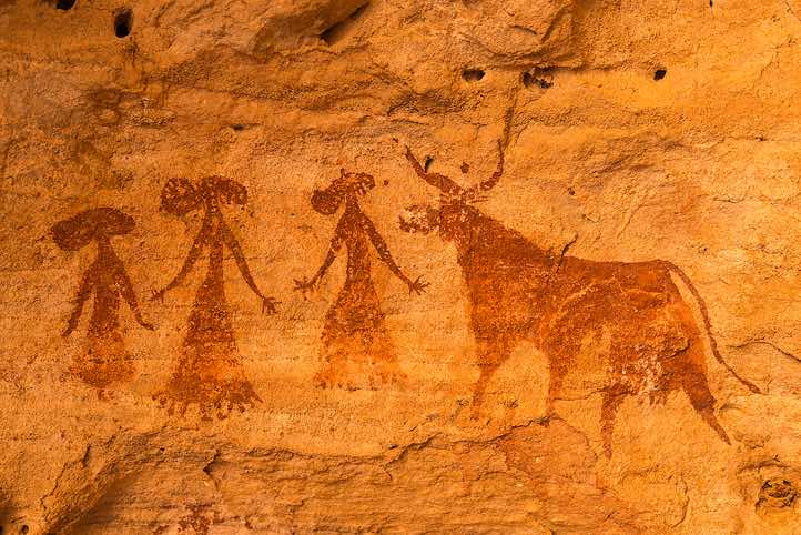 Rock painting of three women wearing elaborate dresses and hats beside a cow, Terkei West, Ennedi, northeastern Chad