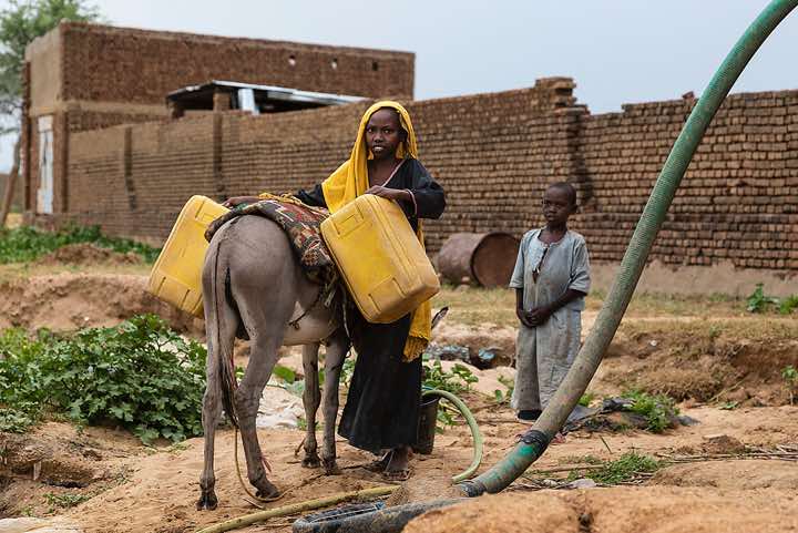 Girl fills up water canisters at a well, Abéché