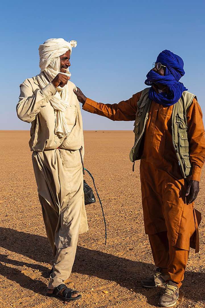 Camel herder (left) receives a gift of tea and sugar from our local guide and driver Omar