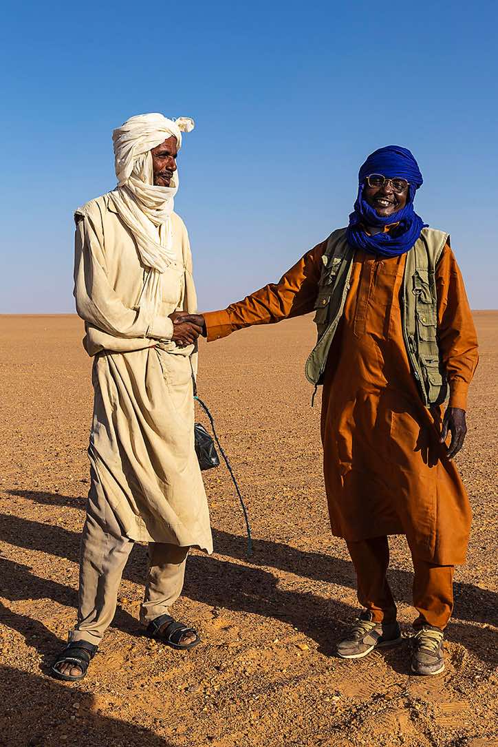 Camel herder (left) receives a gift of tea and sugar from our local guide and driver Omar