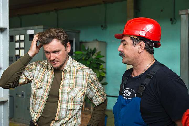 An employee of the geothermal power plant answers questions that Ivan tries to translate, Pauzhetka village