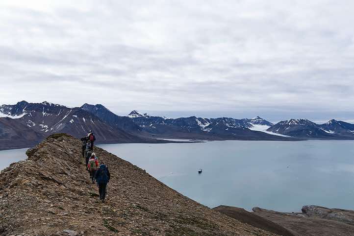 Hiking group walking along Valentinryggen mountain ridge, St. Jonsfjorden, Oscar II Land