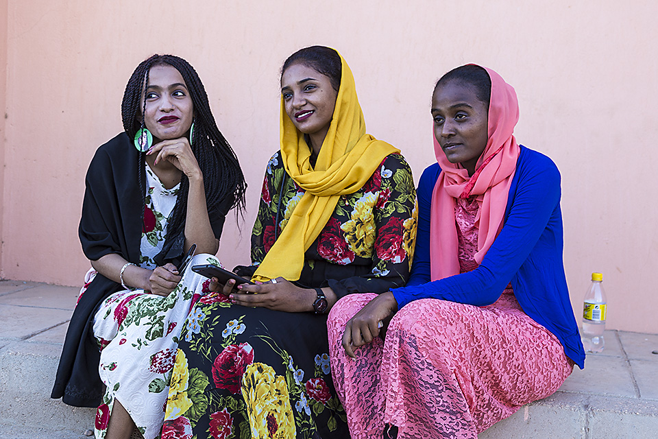 Three young women sitting in front of the Kerma Museum, Northern Sudan